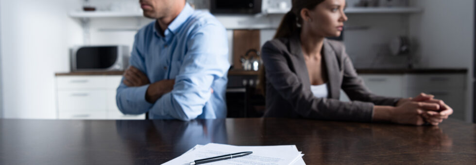 selective focus of couple sitting at table with divorce documents